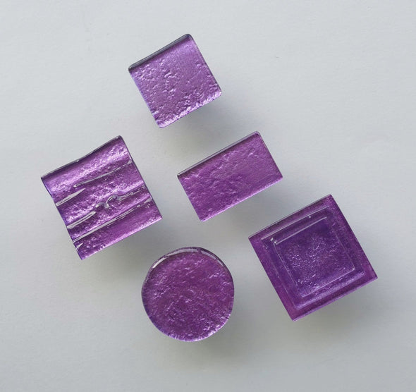 Fired glass cabinet knobs in sparkly bright purple made of round, square and rectangular glass pieces attached over a metal base. Slightly textured glass furniture handles with rounded edges.