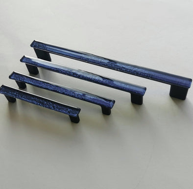 Fired glass cabinet pulls in dark indigo blue made of fine glass sticks attached over a metal base. Slightly textured glass furniture handles with rounded edges.