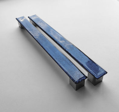 Set of two dark indigo blue fired glass fridge pulls made of long glass sticks attached over a silvery metal base. Slightly textured glass furniture handles with rounded edges.
