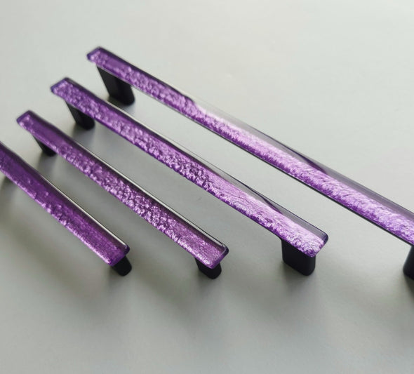 Fired glass cabinet pulls in sparkly bright purple made of fine glass sticks attached over a metal base. Slightly textured glass furniture handles with rounded edges.