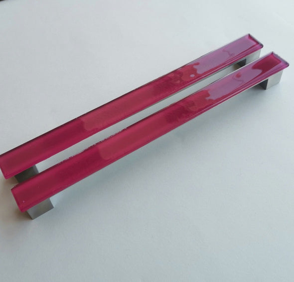 Set of two matte deep red fired glass fridge pulls made of long glass sticks attached over a silvery metal base. Slightly textured glass furniture handles with rounded edges.