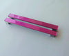 Set of two bright pink fired glass fridge pulls made of long glass sticks attached over a silvery metal base. Slightly textured glass furniture handles with rounded edges.