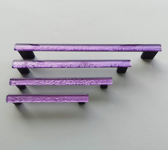 Fired glass cabinet pulls in sparkly bright purple made of fine glass sticks attached over a metal base. Slightly textured glass furniture handles with rounded edges.